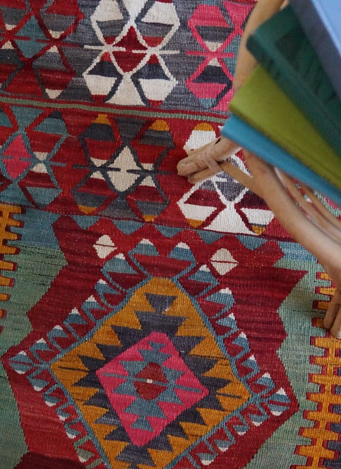 5.5 by 2.9 foot colorful Turkish area rug featuring diamond geometric patterns and bright accent colors