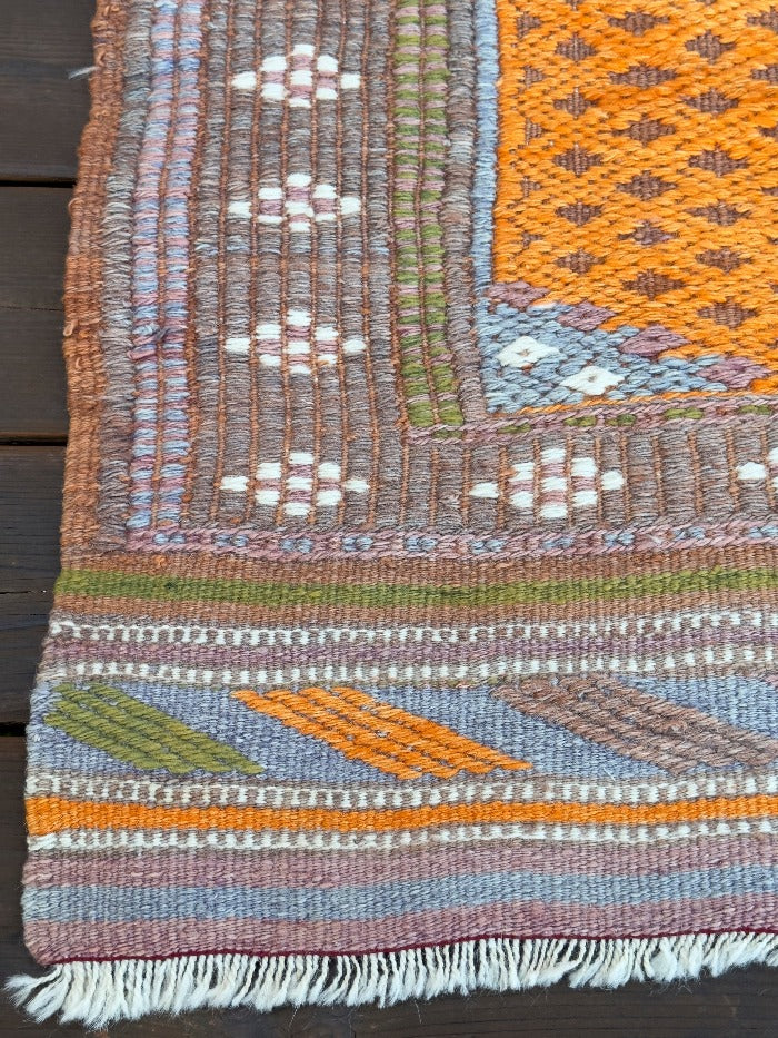 4.5 by 3 colorful turkish area rug featuring bright pops of orange and muted neutrals and pops of blue and green