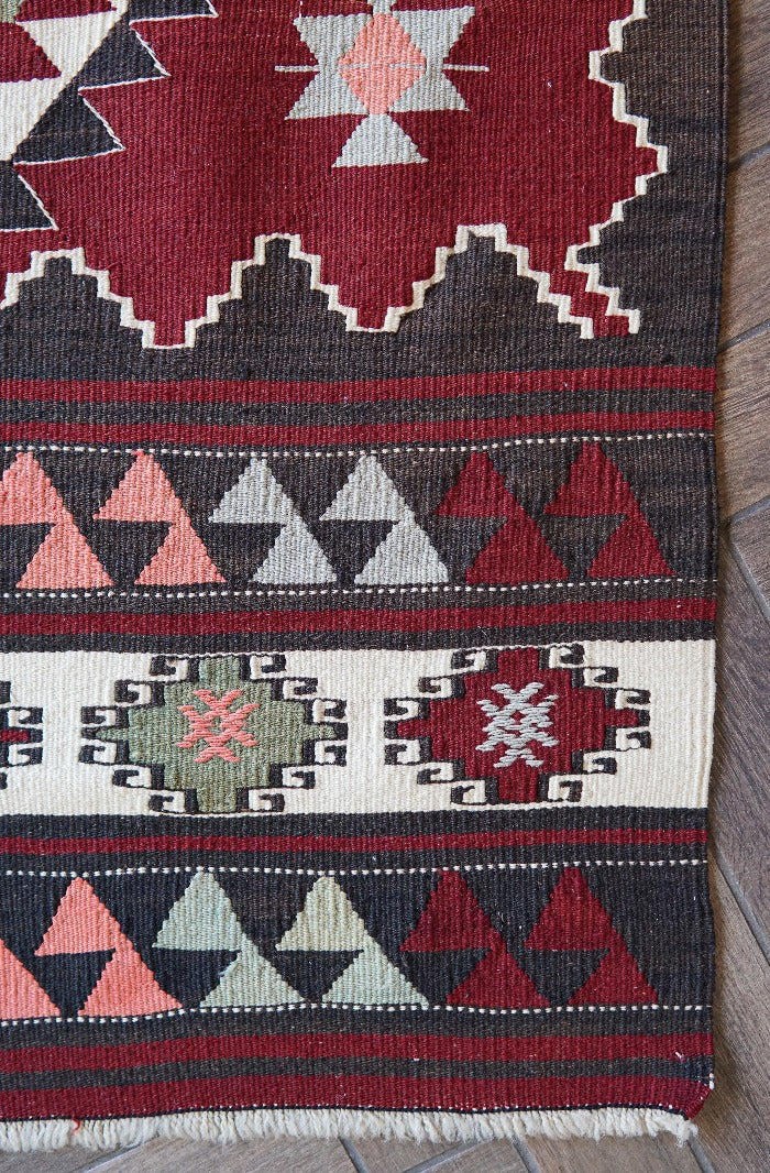8 by 5 foot large red kilim area rug featuring large diamond medallions in the center and multiple striped borders around the outside