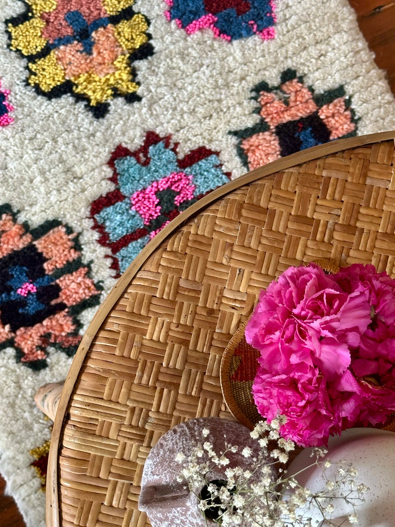 Wicker table with pink flowers on a patterned rug