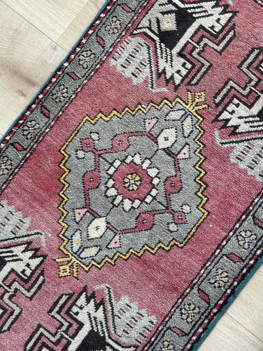 colorful mini Turkish Yastik, with a blue and mauve floral border and inner motif with geometric design in each corner