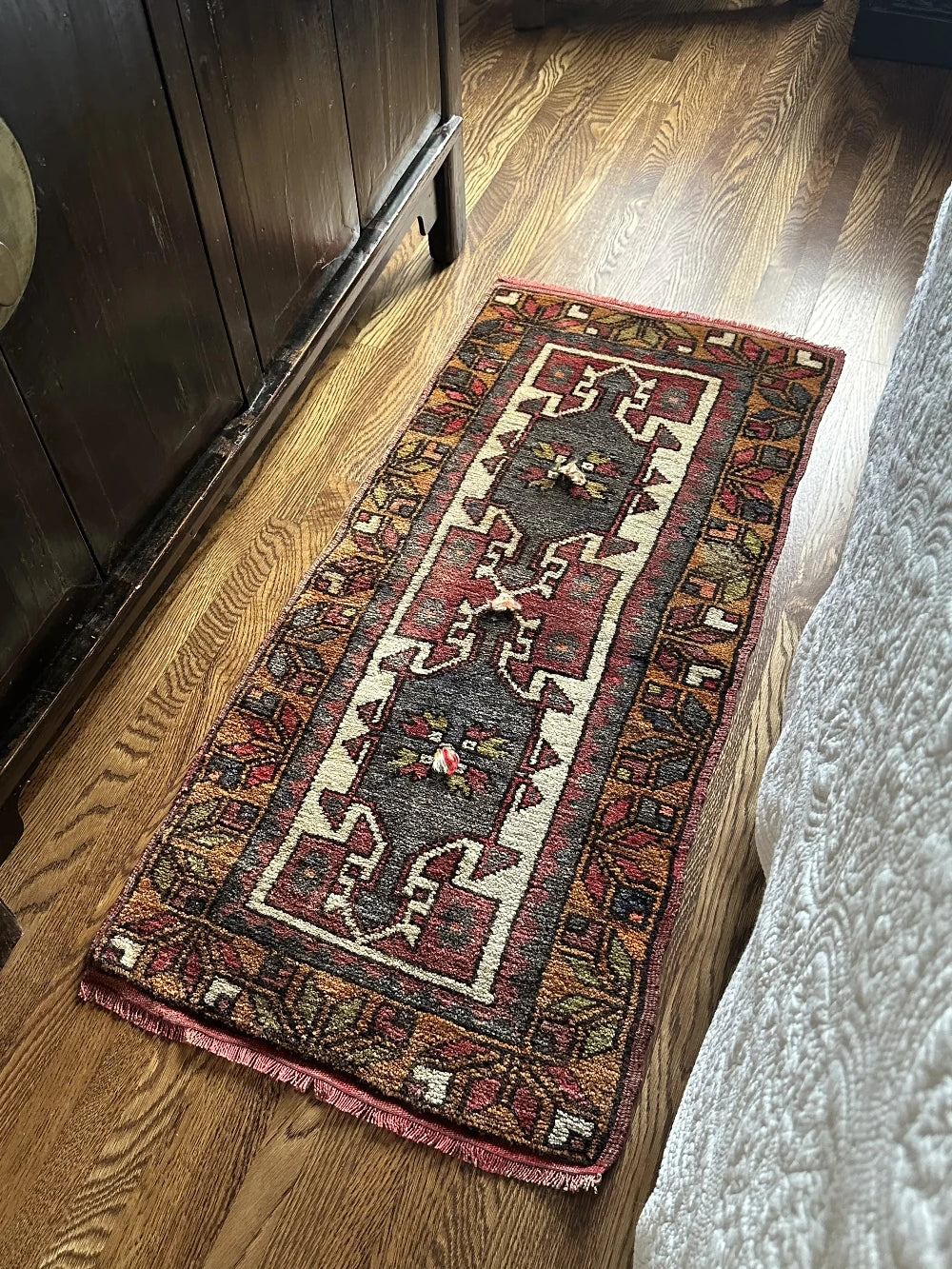 colorful mini turkish rug featuring pops of orange, green, navy and mauve and geometric patterns throughout