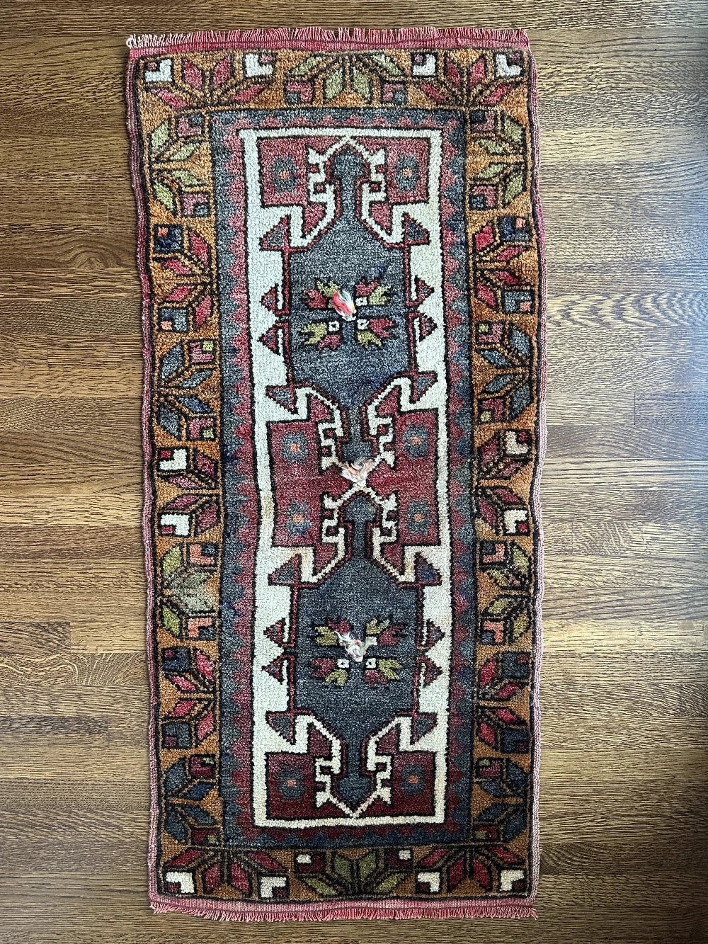 colorful mini turkish rug featuring pops of orange, green, navy and mauve and geometric patterns throughout