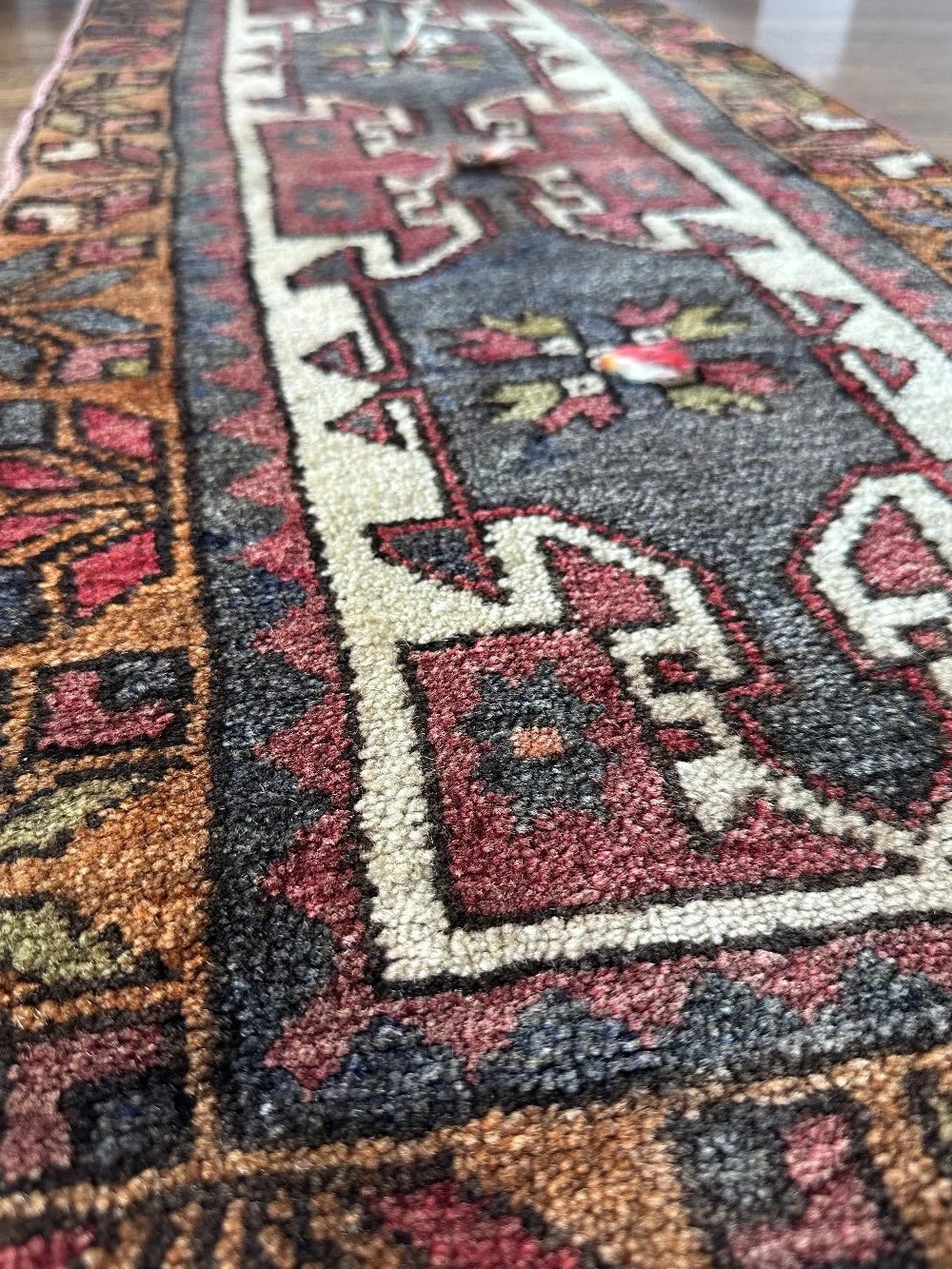 colorful mini turkish rug featuring pops of orange, green, navy and mauve and geometric patterns throughout