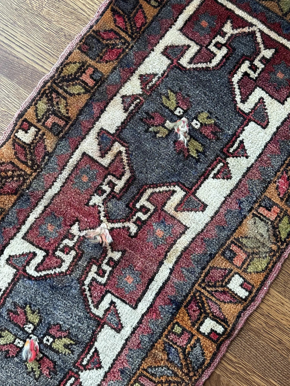 colorful mini turkish rug featuring pops of orange, green, navy and mauve and geometric patterns throughout