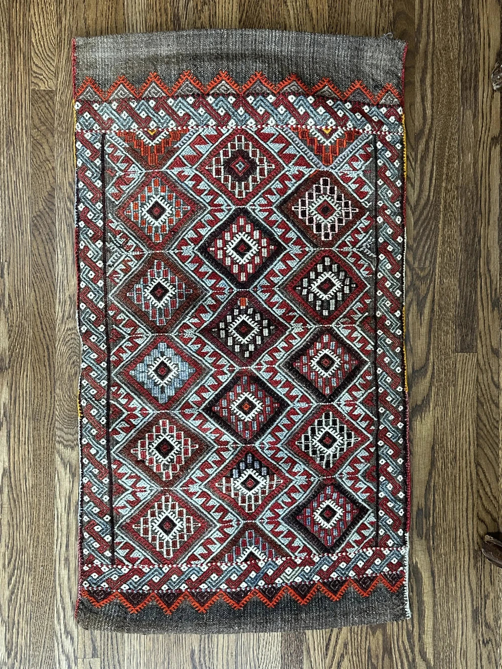 Mini Turkish Rug featuring pops of red and light blue with a repeating diamond pattern throughout