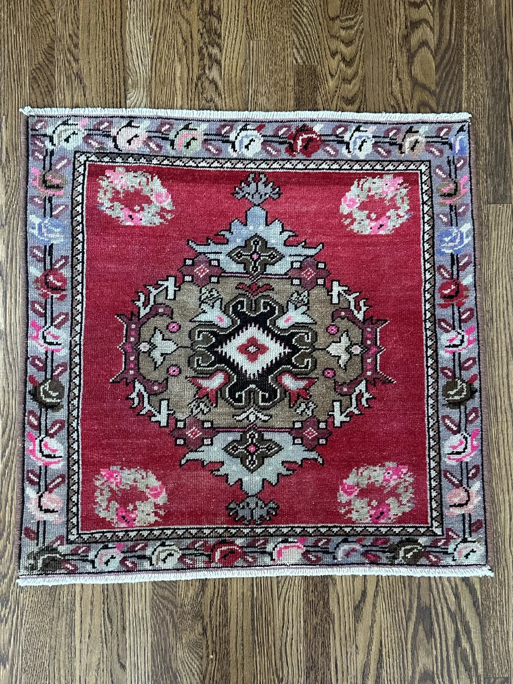 square mini red Turkish rug with a rose patterned border and large geometric medallion center
