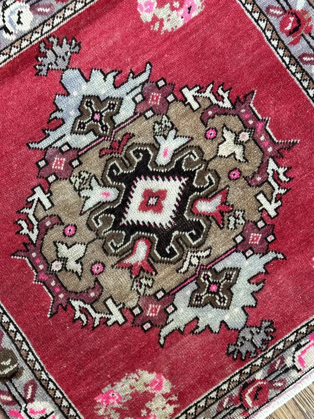 square mini red Turkish rug with a rose patterned border and large geometric medallion center