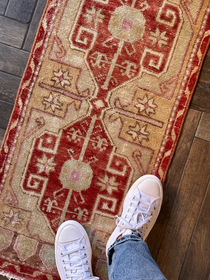 4 by 2 small Turkish area rug featuring deep red hues and light sand and tan coloring with two large medallions in the center bordered by geometric shapes and florals