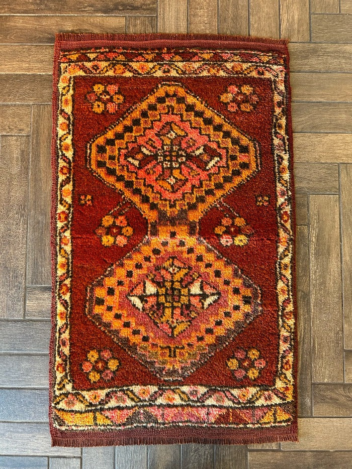3 by 2 small Turkish area rug featuring sunset orange, red and pink coloring and two large medallions on the center with flowers around