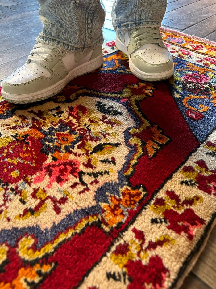 2 x 4 small floral Turkish area rug featuring rose and other floral patterns and deep red hues with bright pops of orange pink blue and green.