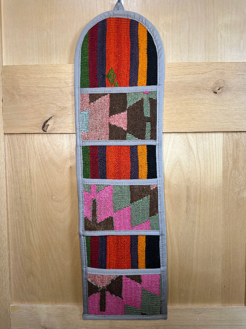 Decorative, handmade Turkish rug wall organizer with vibrant stripe designs and 3 storage pockets. Upcycled vintage textile art by High Pile Designs.
