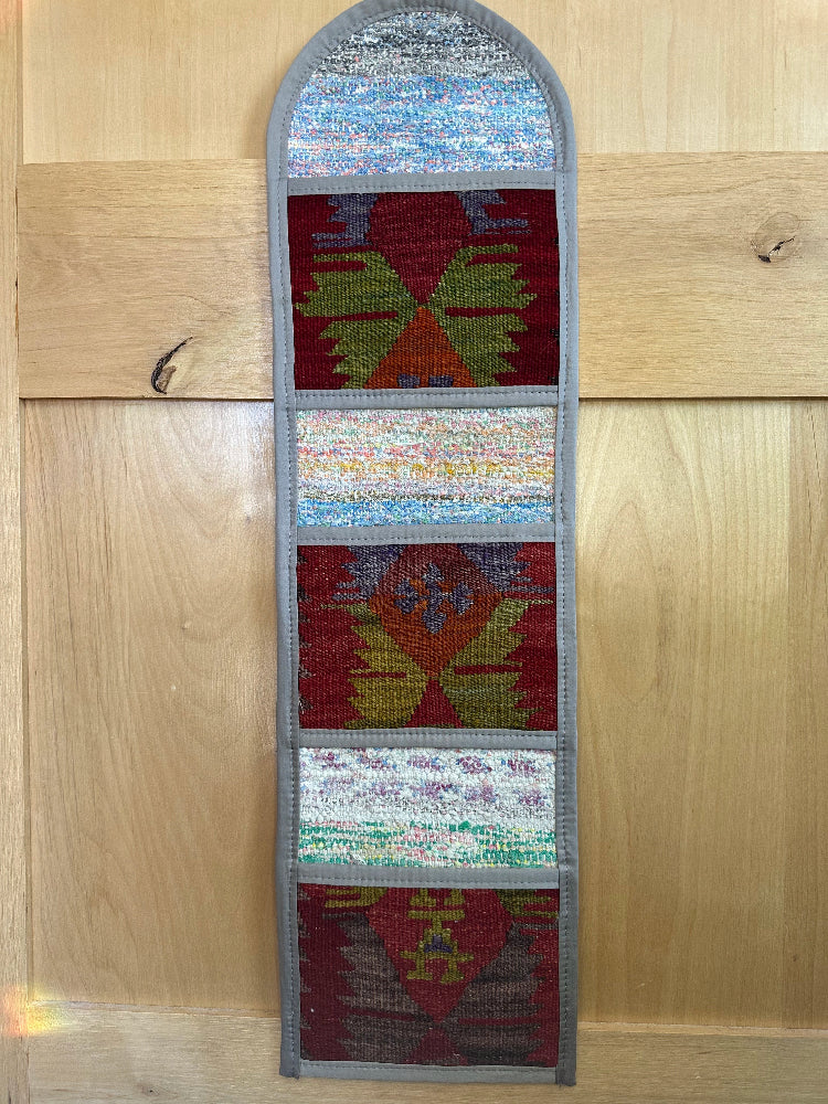 Decorative, handmade Turkish rug wall organizer with vibrant stripe designs and 3 storage pockets. Upcycled vintage textile art by High Pile Designs. Featuring wrapped gifts.