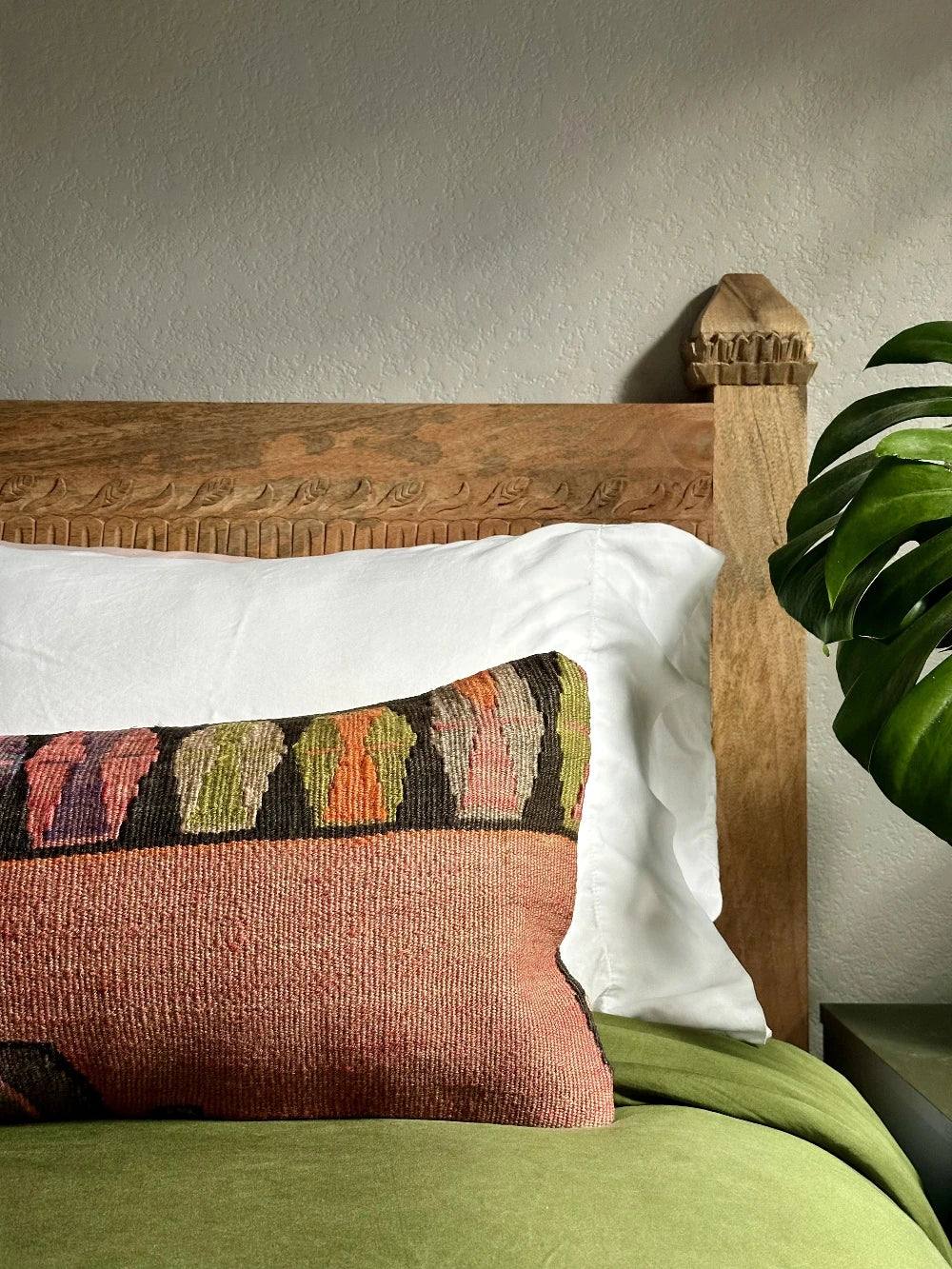 12 by 36 colorful turkish lumbar pillow featuring an all over merlot coloring and a geometric multi-colored band at the top with pops of pink, purple, green and orange