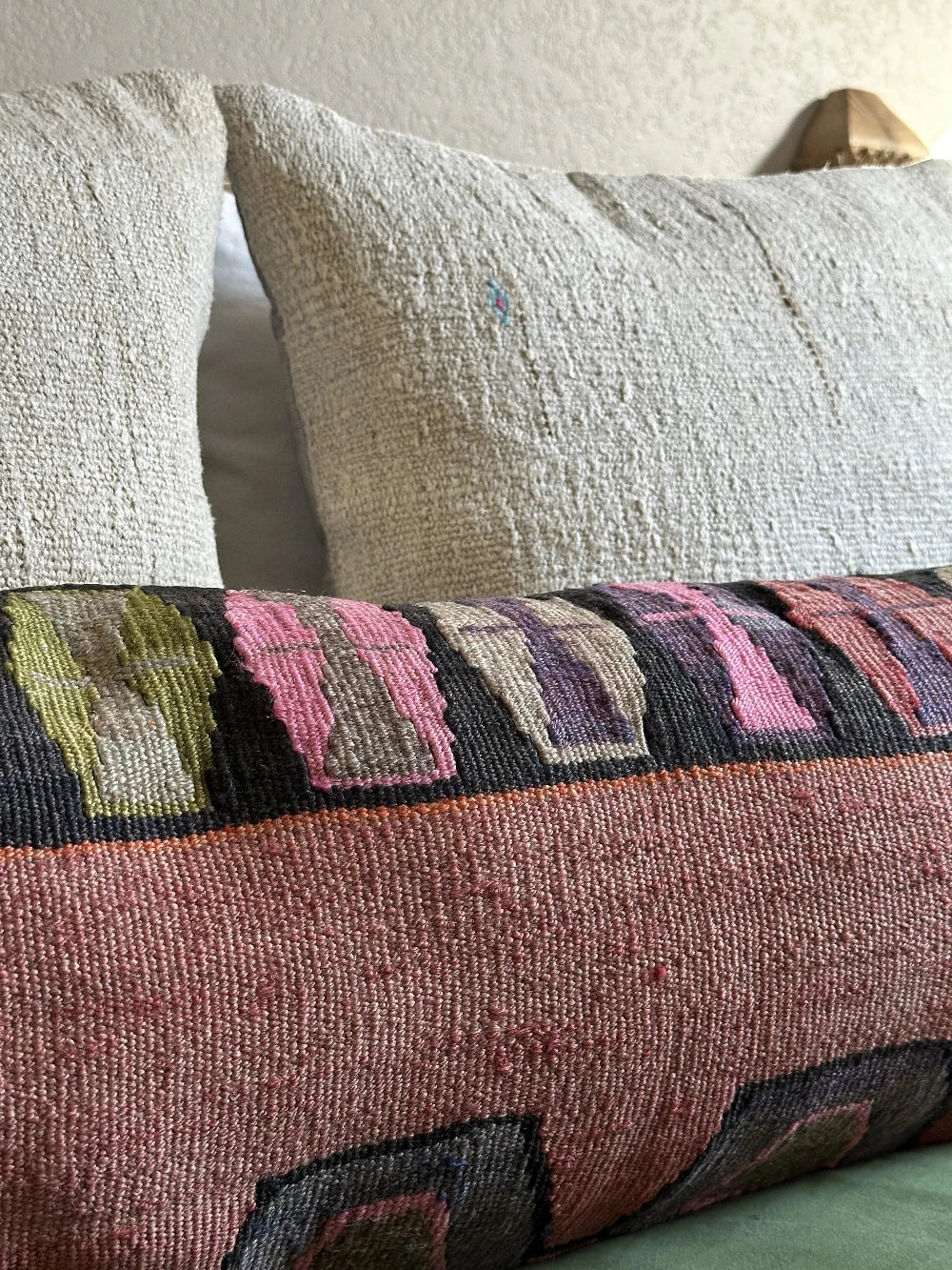 12 by 36 colorful turkish lumbar pillow featuring an all over merlot coloring and a geometric multi-colored band at the top with pops of pink, purple, green and orange