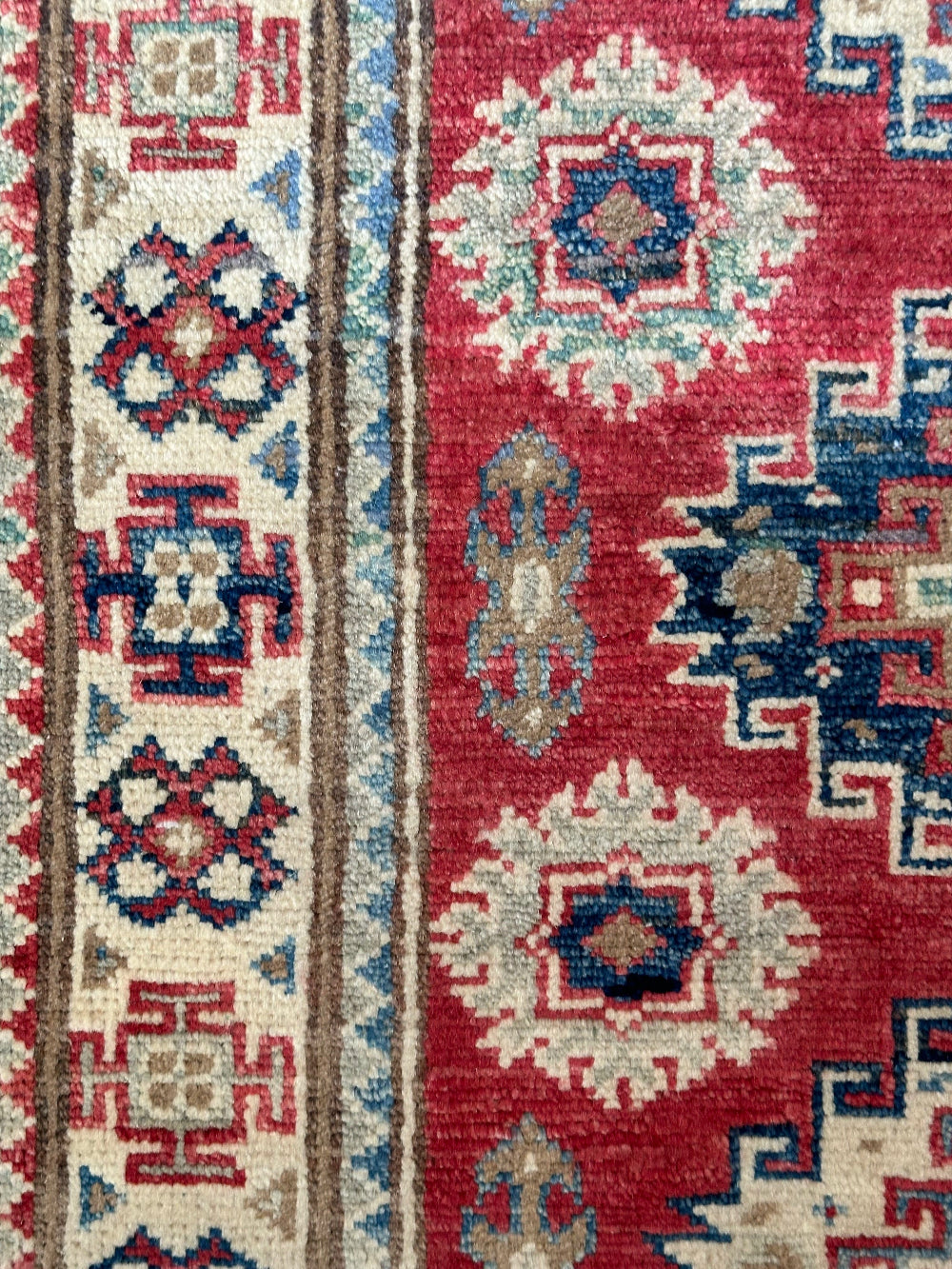 Hand-knotted 2x3 foot mini pile rug featuring a colorful geometric design, large central motif and geometric border - wool material with pops of red, light blue, navy and white.