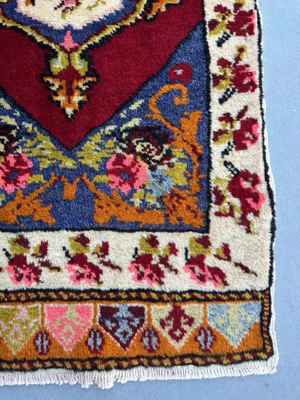 2 x 4 small floral Turkish area rug featuring rose and other floral patterns and deep red hues with bright pops of orange pink blue and green.