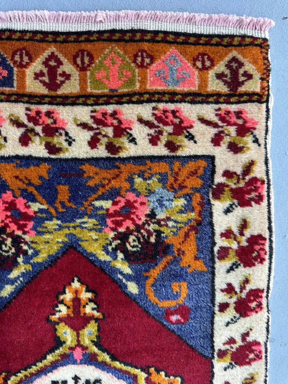 2 x 4 small floral Turkish area rug featuring rose and other floral patterns and deep red hues with bright pops of orange pink blue and green.