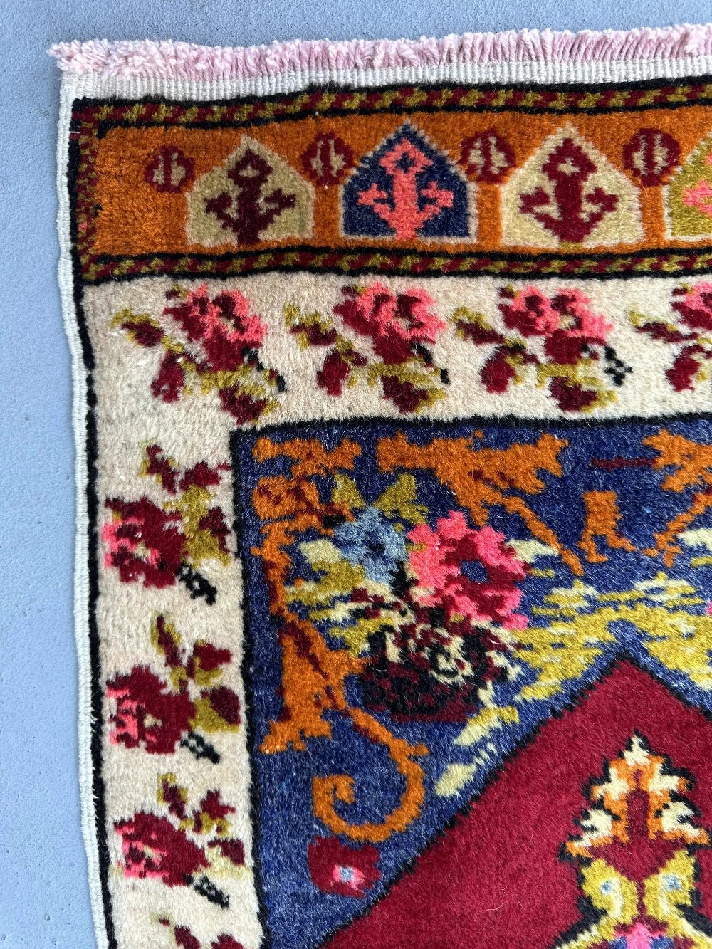 2 x 4 small floral Turkish area rug featuring rose and other floral patterns and deep red hues with bright pops of orange pink blue and green.