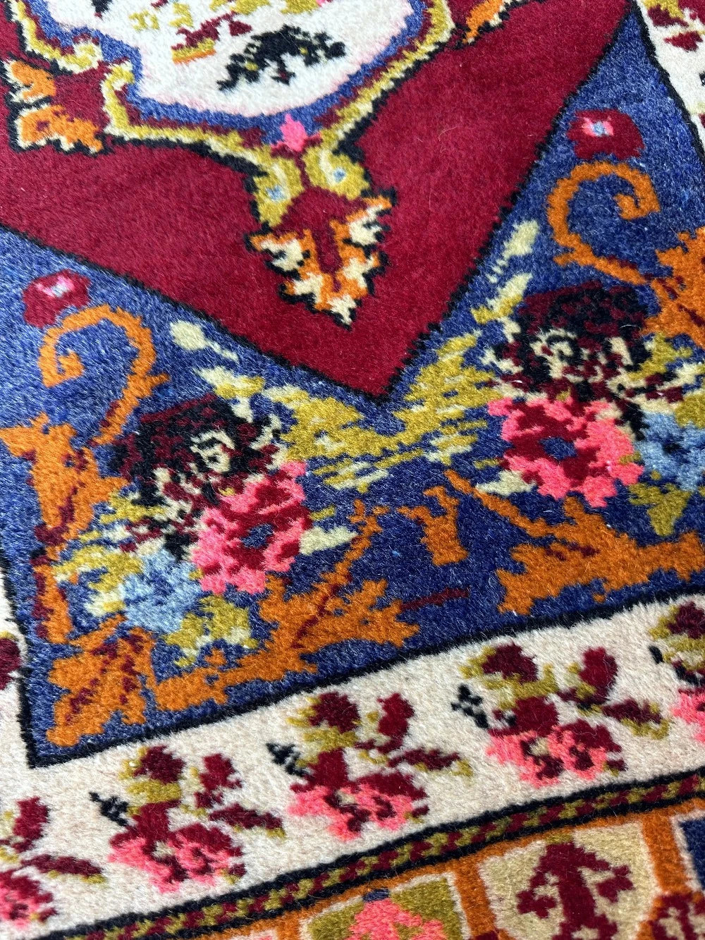 2 x 4 small floral Turkish area rug featuring rose and other floral patterns and deep red hues with bright pops of orange pink blue and green.