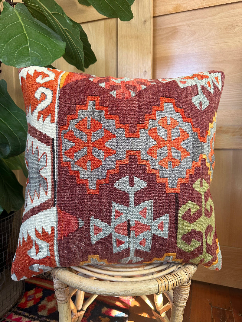Sustainably made kilim pillow from upcycled Turkish wool rugs. Handwoven by artisans, featuring bold tribal patterns in rust, gray, olive, and cream tones.