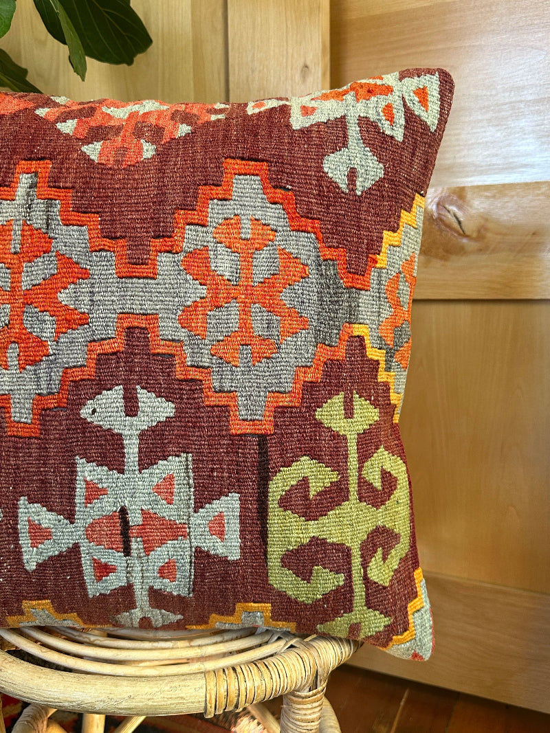 Sustainably made kilim pillow from upcycled Turkish wool rugs. Handwoven by artisans, featuring bold tribal patterns in rust, gray, olive, and cream tones.