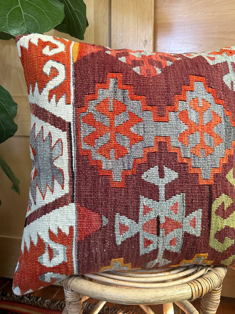 Sustainably made kilim pillow from upcycled Turkish wool rugs. Handwoven by artisans, featuring bold tribal patterns in rust, gray, olive, and cream tones.