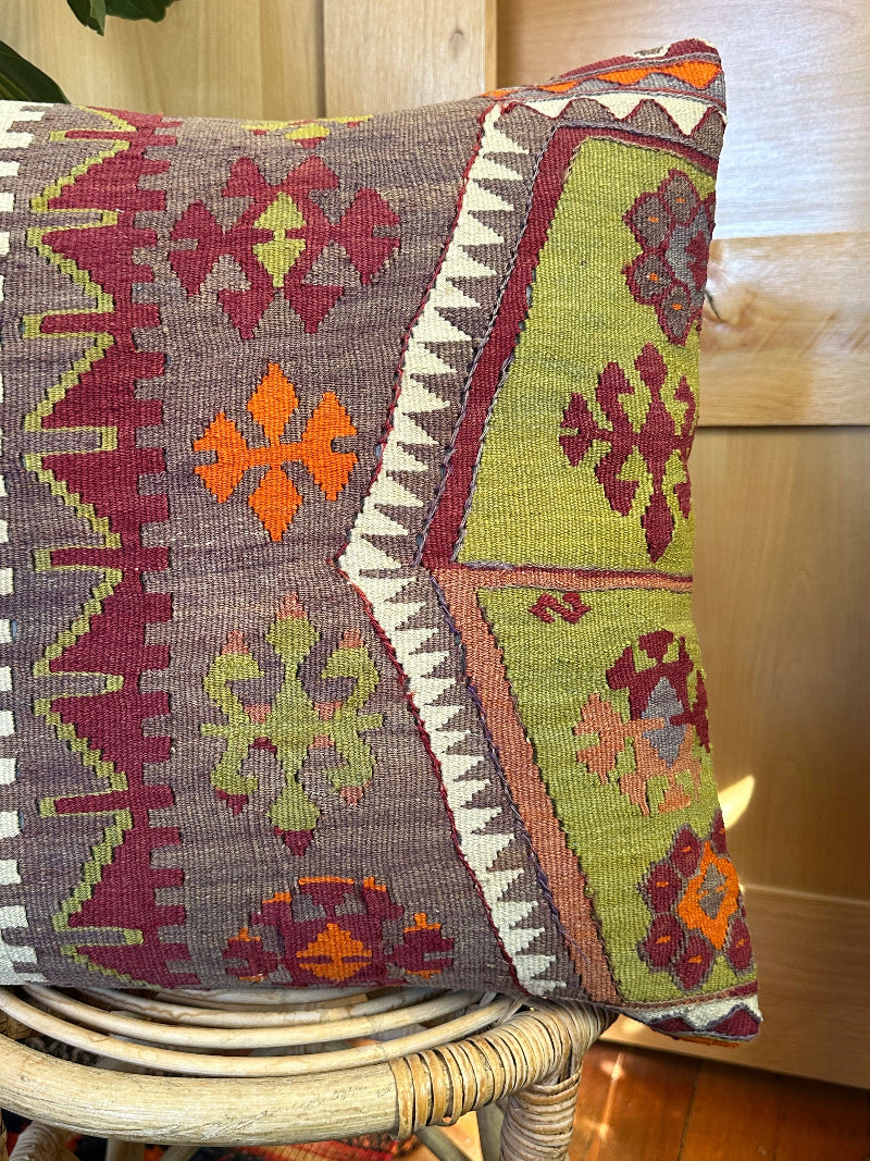 Eco-conscious kilim pillow handcrafted from repurposed Turkish rugs. Features rich geometric patterns in olive, rust, plum, and ivory tones