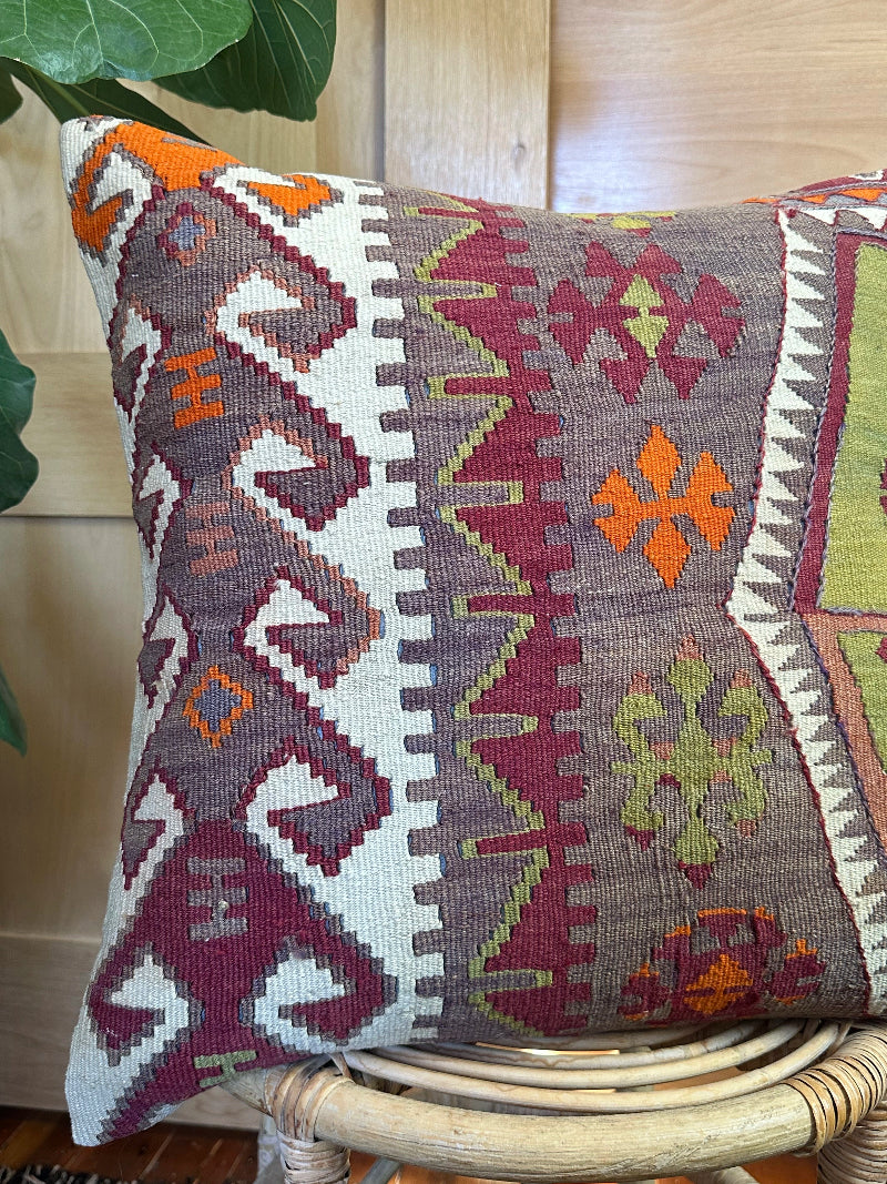 Eco-conscious kilim pillow handcrafted from repurposed Turkish rugs. Features rich geometric patterns in olive, rust, plum, and ivory tones