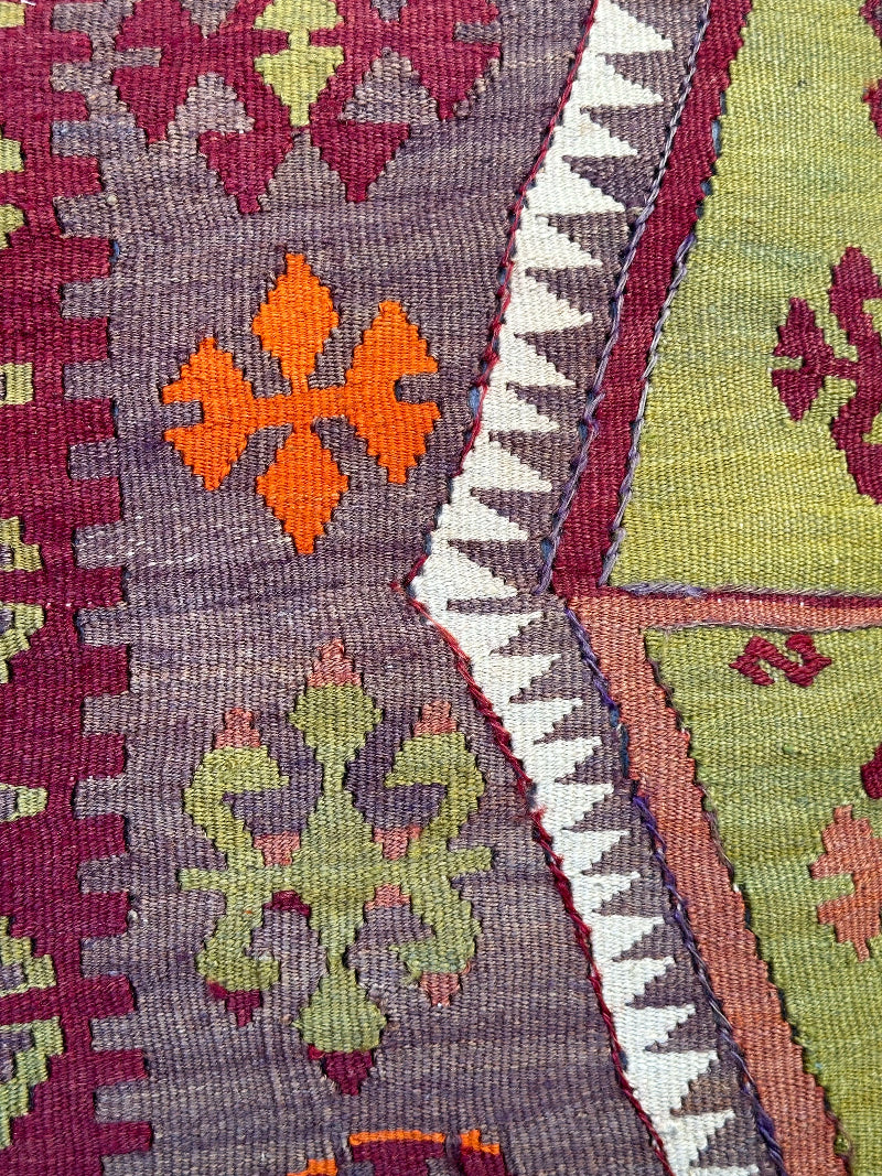 Eco-conscious kilim pillow handcrafted from repurposed Turkish rugs. Features rich geometric patterns in olive, rust, plum, and ivory tones
