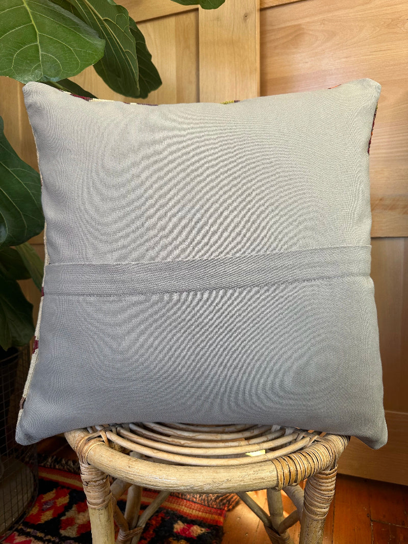 Eco-conscious kilim pillow handcrafted from repurposed Turkish rugs. Features rich geometric patterns in olive, rust, plum, and ivory tones