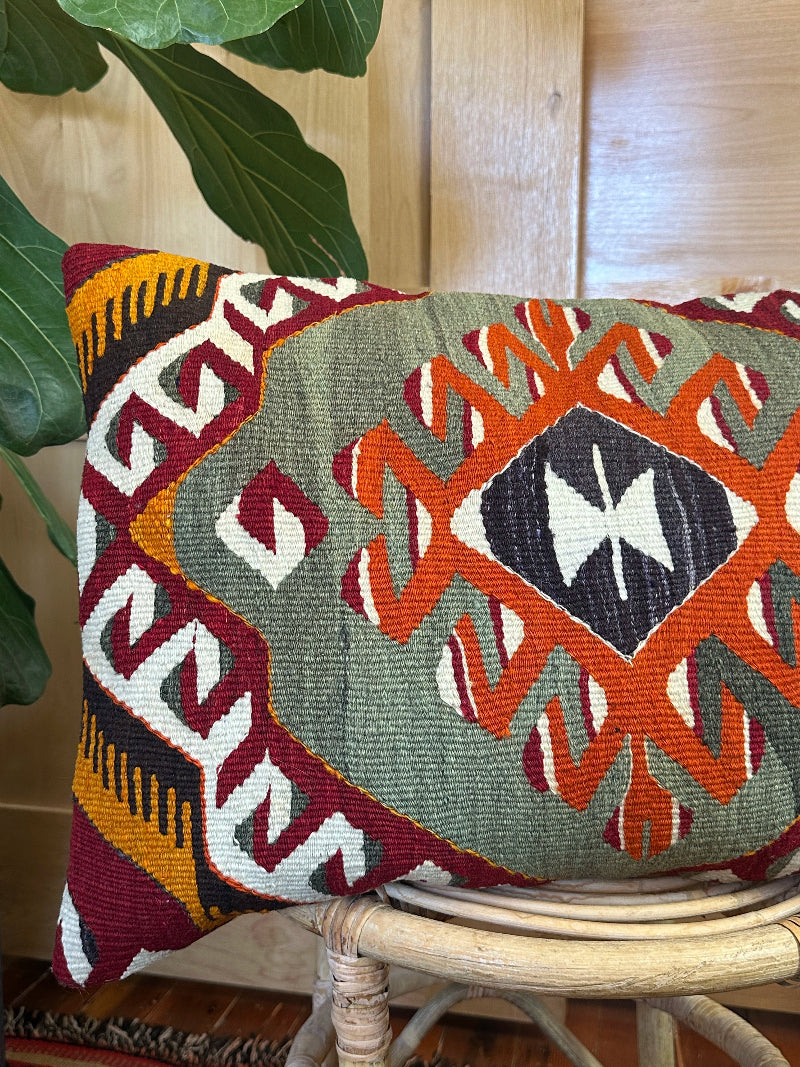 16 by 24 Decorative pillow with geometric pattern on a wooden stool indoors