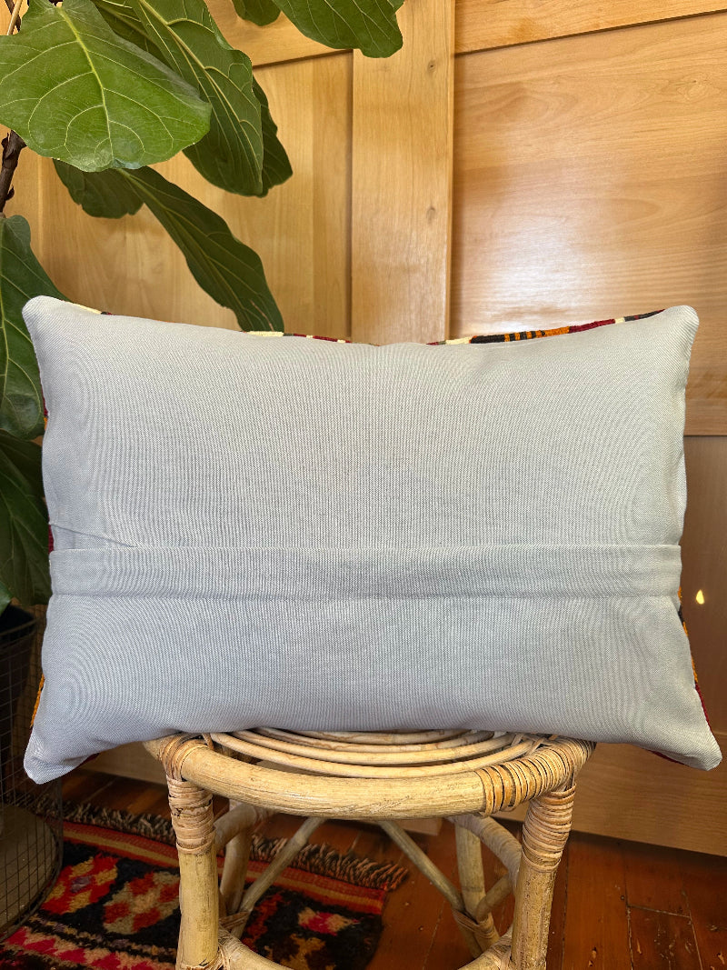 16 by 24 Decorative pillow with geometric pattern on a wooden stool indoors