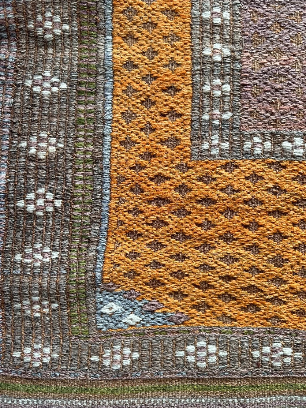 4.5 by 3 colorful turkish area rug featuring bright pops of orange and muted neutrals and pops of blue and green