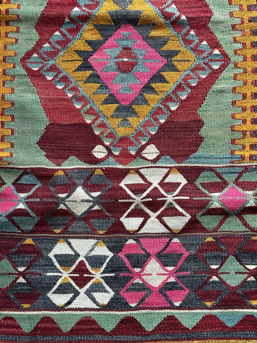 5.5 by 2.9 foot colorful Turkish area rug featuring diamond geometric patterns and bright accent colors