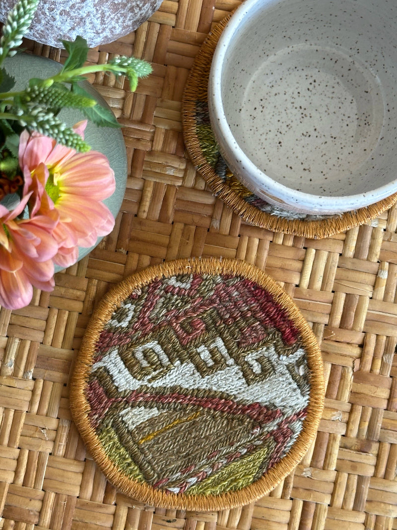 Handmade Turkish rug coasters with orange trim, repurposed from vintage rugs for a unique, sustainable home decor accent