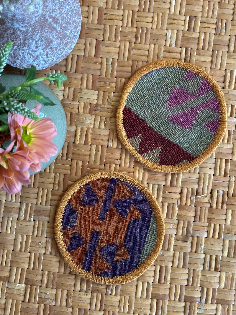 Handmade Turkish rug coasters with orange trim, repurposed from vintage rugs for a unique, sustainable home decor accent