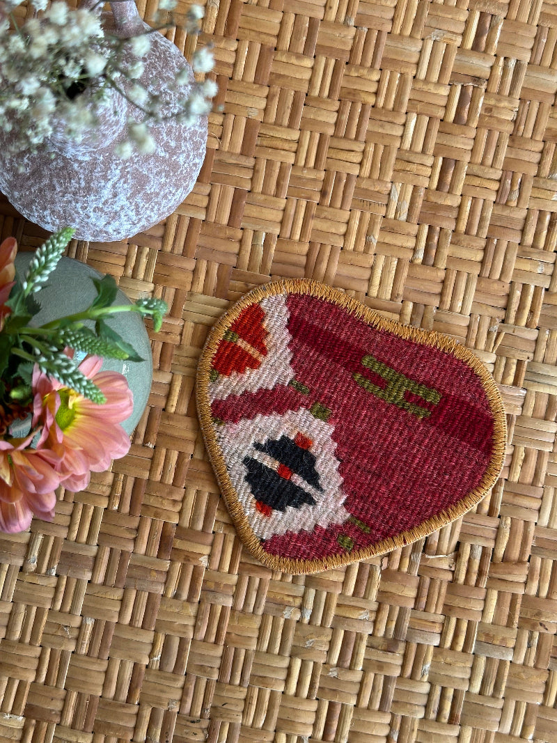 Heart-shaped Turkish rug hot plate with red tones and geometric patterns, handcrafted from repurposed vintage rugs for a unique, sustainable home accent