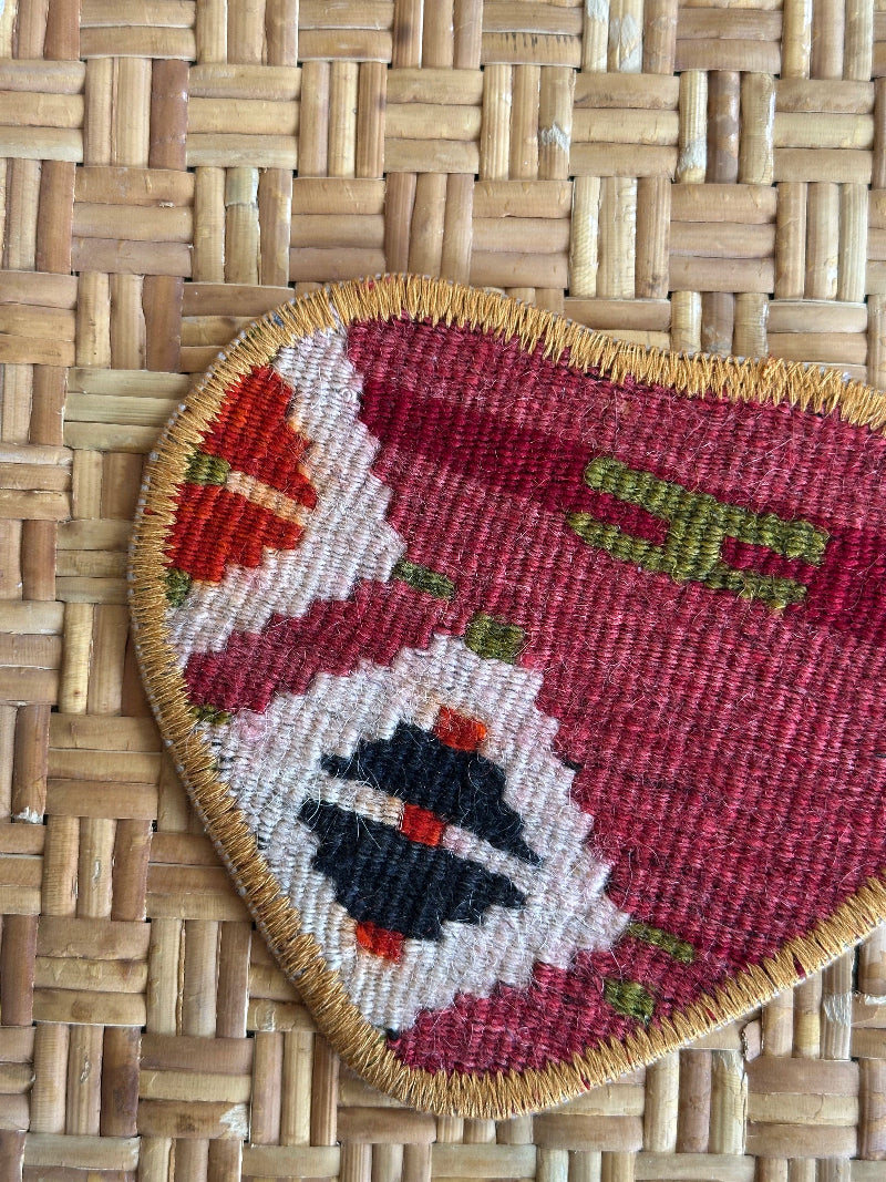 Heart-shaped Turkish rug hot plate with red tones and geometric patterns, handcrafted from repurposed vintage rugs for a unique, sustainable home accent