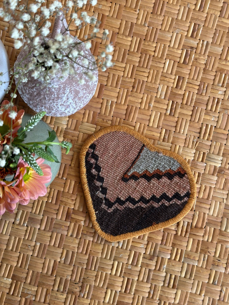 six inch heart-shaped Turkish rug hot plate made from repurposed vintage rugs with light green and brown tones and embroidered trim, perfect for hot pans, plants, or decor.