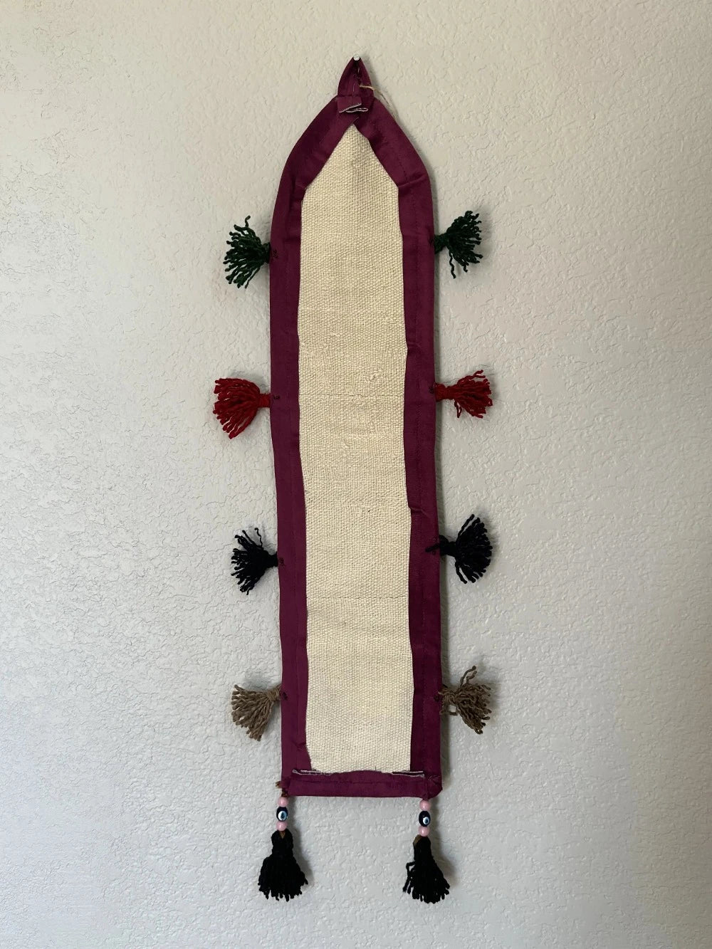 multi-colored three pocket wall organizer made from scraps of colorful Turkish kilim rugs with yarn tassels at each end