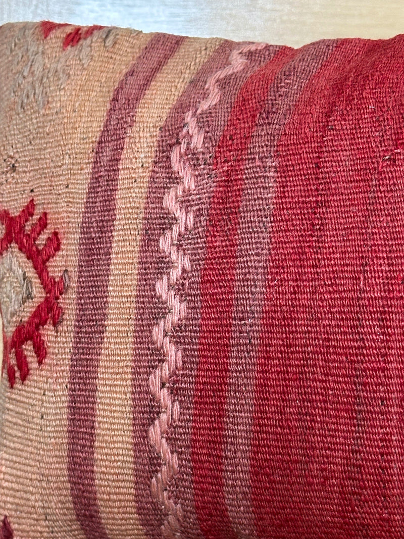 Extra-long vintage Turkish kilim pillow in red, pink, and earthy tones with vertical stripes and traditional geometric motifs, handwoven from wool.