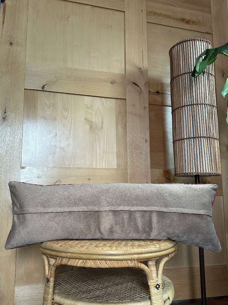 Extra-long vintage Turkish kilim pillow in red, pink, and earthy tones with vertical stripes and traditional geometric motifs, handwoven from wool.