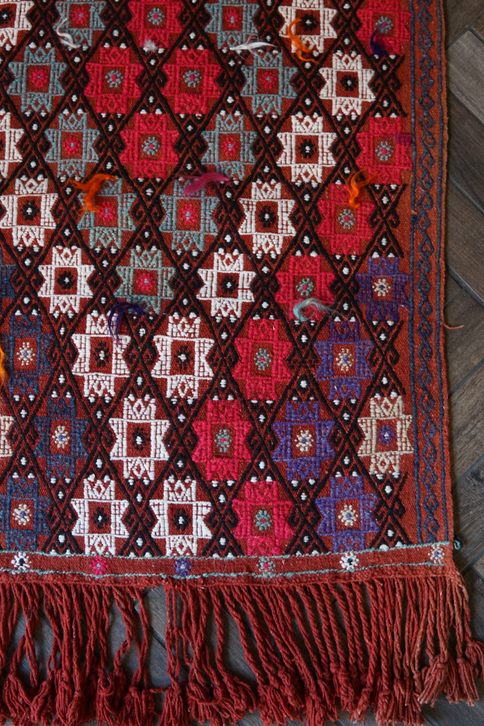 5.5 by 3.8 ft red Turkish area rug and tapestry with fringe, featuring white, pink, purple and blue 8-pointed stars