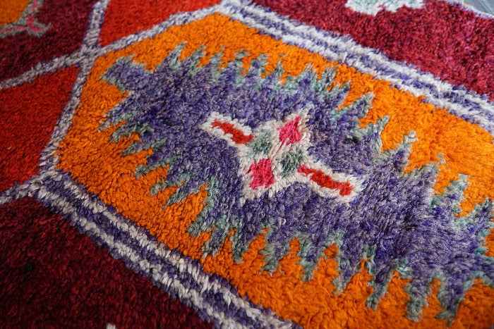 11.5 foot by 3 foot high pile Turkish Herki runner with long shaggy pile and a southwestern feel, orange, red and maroon base coloring and accents of purple, light blue and pink.