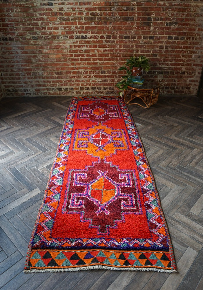10.8 by 3.3 foot high pile turkish runner featuring bright pops of red and orange and three large medallions. Southwestern feel and style with a beautiful diamond pattern around the border
