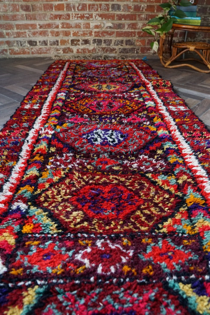 10.5 by 3 foot colorful Turkish runner featuring high pile and multicolored geometric patterns throughout
