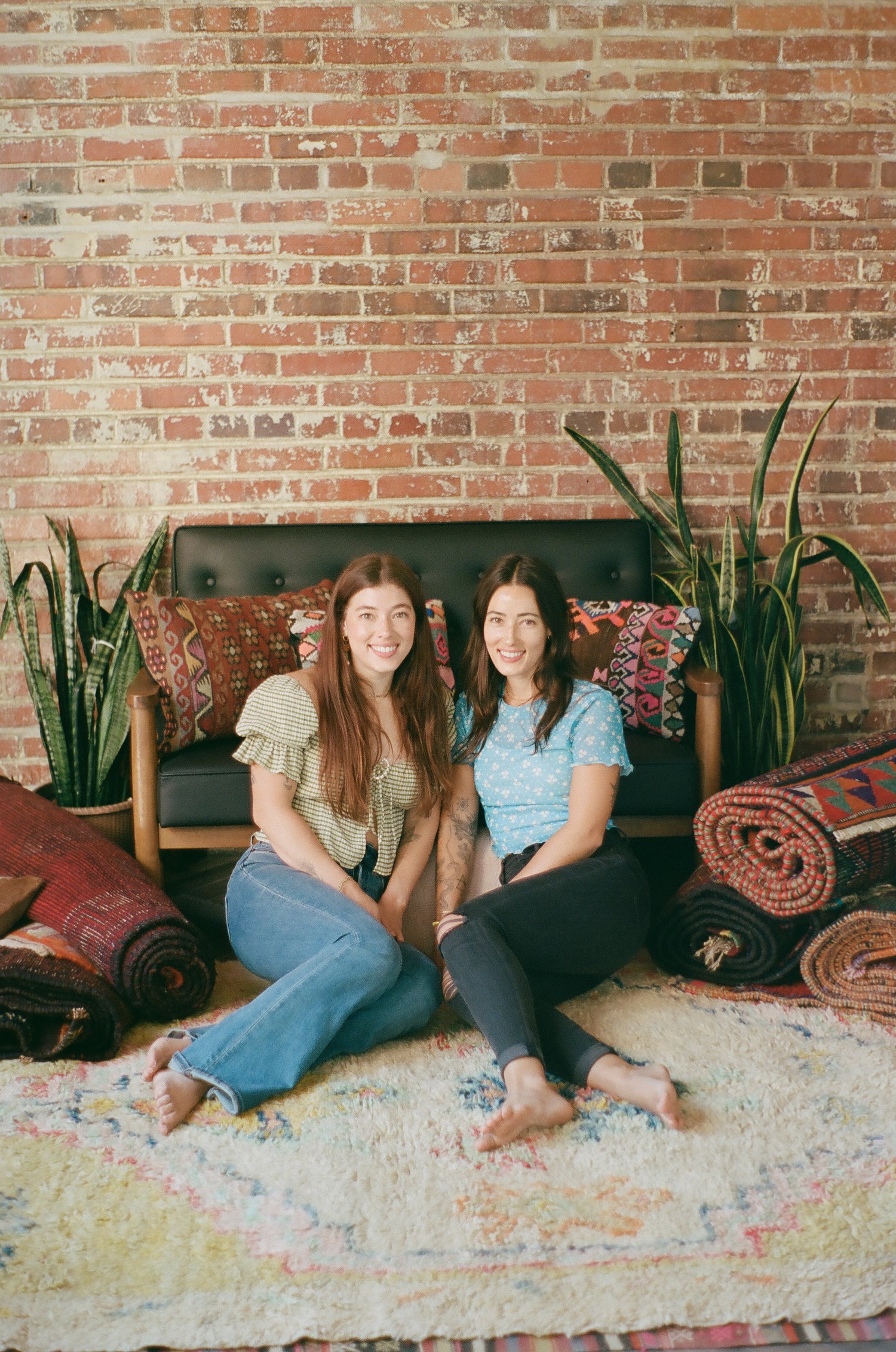 co-founders of High Pile Designs sitting on a muted Turkish rug with beautiful rugs and pillows surrounding them