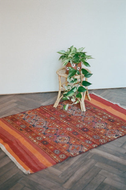 5 by 3 red and orange Turkish area rug featuring a striped pattern on the outside edges and a central striped pattern with geometric shapes and embroidery