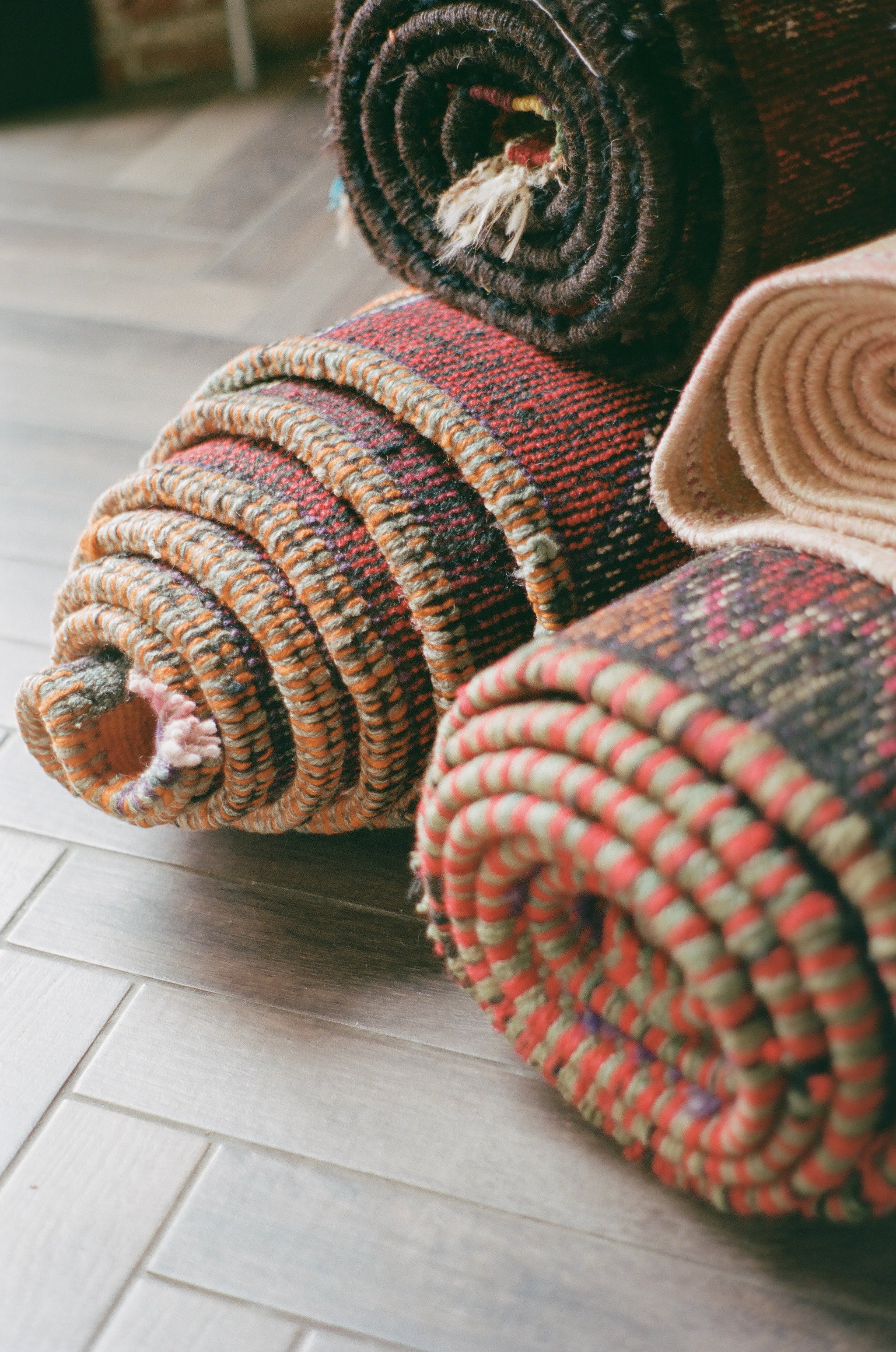 close up shot of colorful rugs rolled up and stacked on top of one another